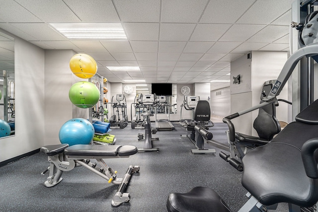 exercise room with baseboards and a paneled ceiling