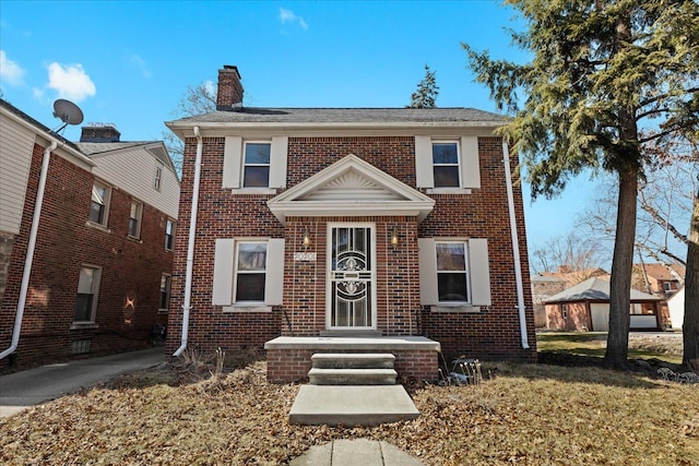 view of front of house with a front lawn, brick siding, and a chimney