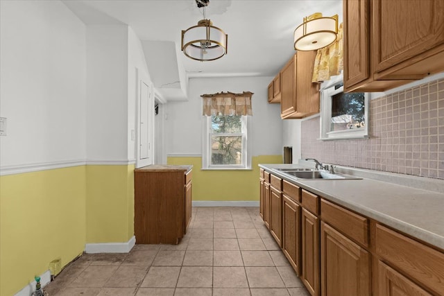 kitchen featuring a sink, tasteful backsplash, light countertops, light tile patterned floors, and baseboards