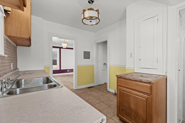 kitchen with backsplash, pendant lighting, light countertops, light tile patterned flooring, and a sink