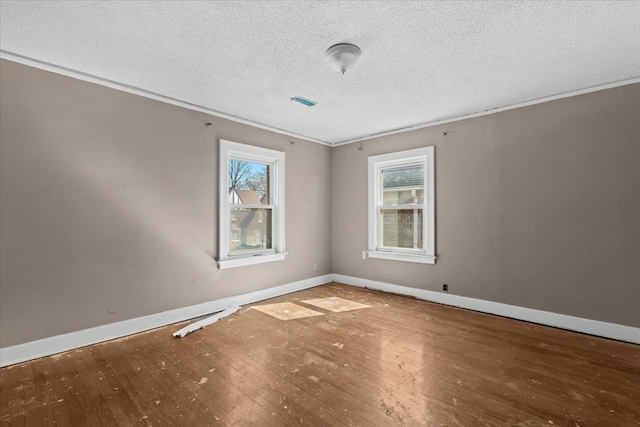 spare room featuring a wealth of natural light, baseboards, and hardwood / wood-style flooring