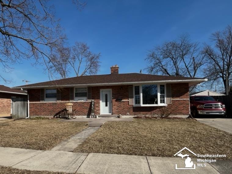 view of front facade featuring a front yard, brick siding, and a chimney