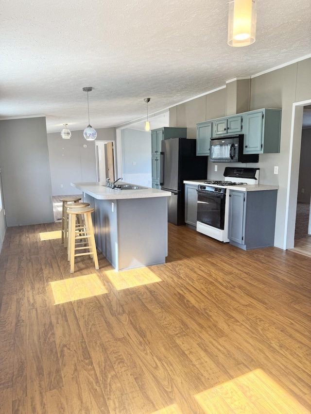 kitchen featuring light wood-type flooring, range with gas stovetop, black microwave, and light countertops