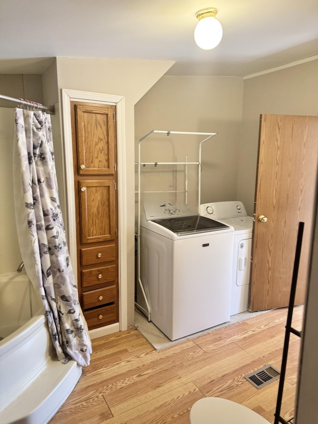 clothes washing area with laundry area, washer and dryer, light wood-style flooring, and visible vents