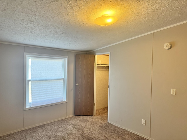 unfurnished bedroom featuring a spacious closet, a closet, carpet floors, and a textured ceiling