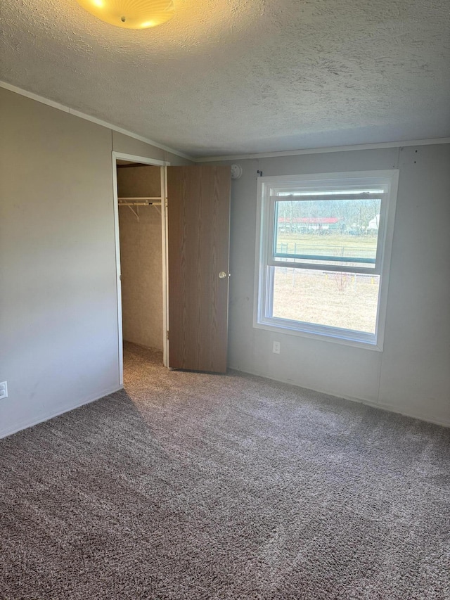 unfurnished bedroom with crown molding, carpet flooring, a closet, and a textured ceiling