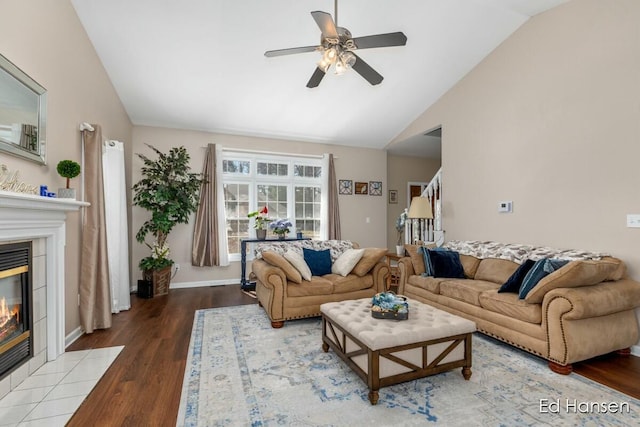 living room featuring wood finished floors, lofted ceiling, a fireplace, ceiling fan, and stairs