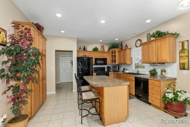 kitchen with a kitchen island, a breakfast bar, a sink, decorative backsplash, and black appliances