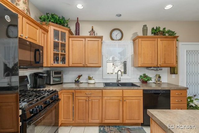 kitchen with black appliances, a sink, tasteful backsplash, recessed lighting, and glass insert cabinets