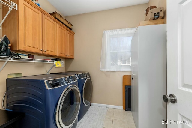 laundry area featuring cabinet space, light tile patterned floors, independent washer and dryer, and baseboards