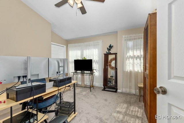 home office with lofted ceiling, a ceiling fan, baseboards, and light carpet