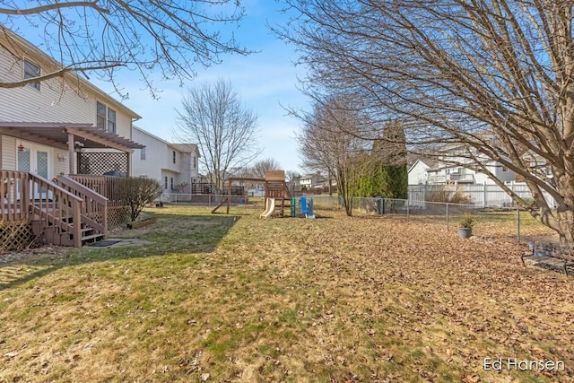 view of yard with a wooden deck, a fenced backyard, and a playground