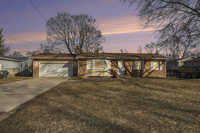 ranch-style home with a front yard, driveway, a chimney, a garage, and brick siding