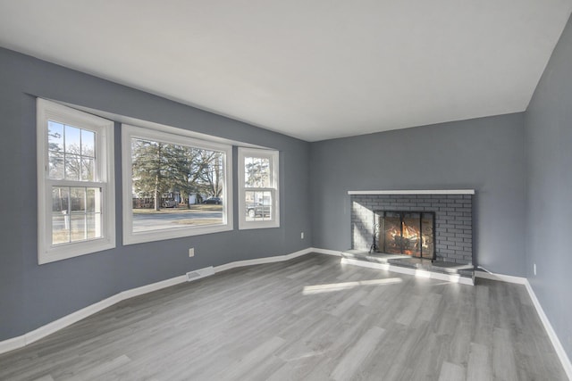 unfurnished living room featuring visible vents, a fireplace, baseboards, and wood finished floors