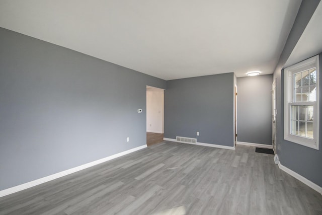 empty room featuring visible vents, wood finished floors, and baseboards