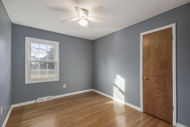 empty room featuring baseboards, wood finished floors, visible vents, and ceiling fan