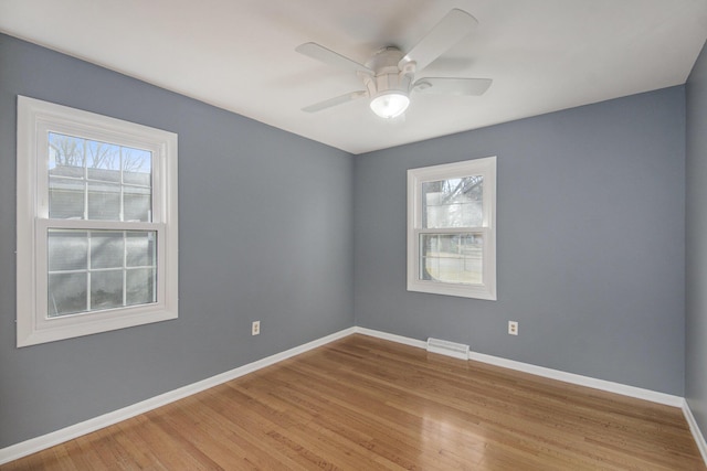 spare room with baseboards, light wood-style floors, and ceiling fan