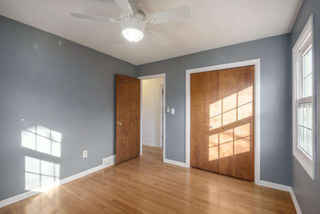 unfurnished bedroom with multiple windows, baseboards, and light wood-type flooring