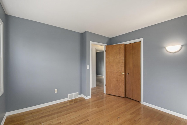 unfurnished bedroom with a closet, visible vents, light wood-style flooring, and baseboards