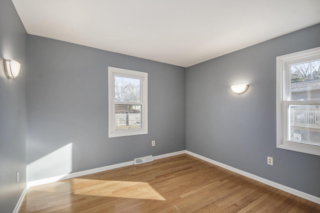 spare room featuring visible vents, wood finished floors, and baseboards