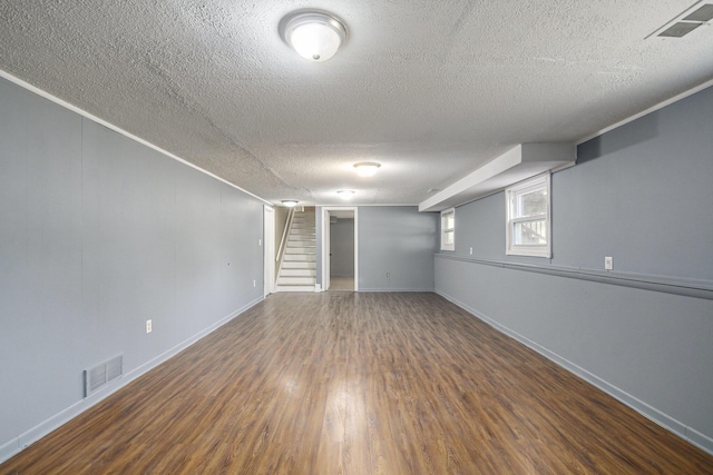 basement with stairway, wood finished floors, visible vents, baseboards, and a textured ceiling