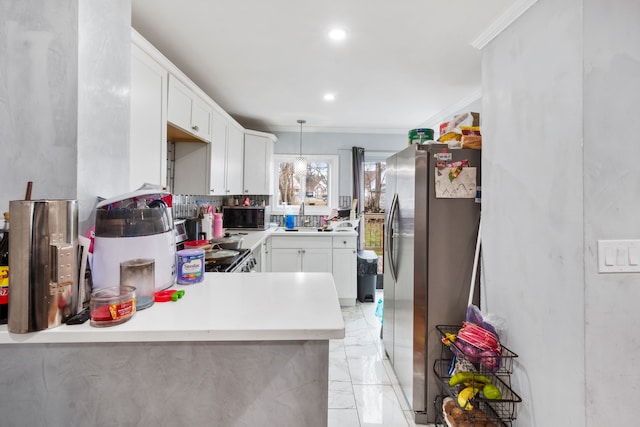 kitchen with light countertops, ornamental molding, white cabinets, stainless steel fridge, and marble finish floor