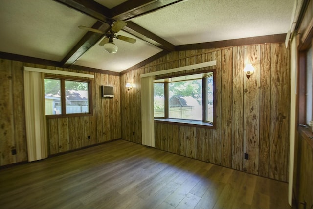 spare room with plenty of natural light, wood finished floors, wood walls, and vaulted ceiling with beams