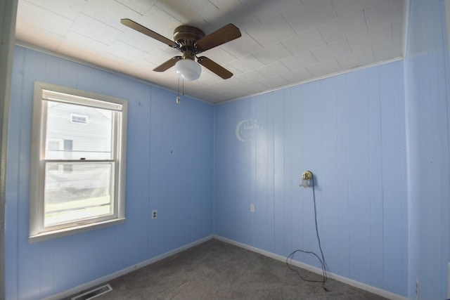 carpeted empty room with baseboards, visible vents, and ceiling fan