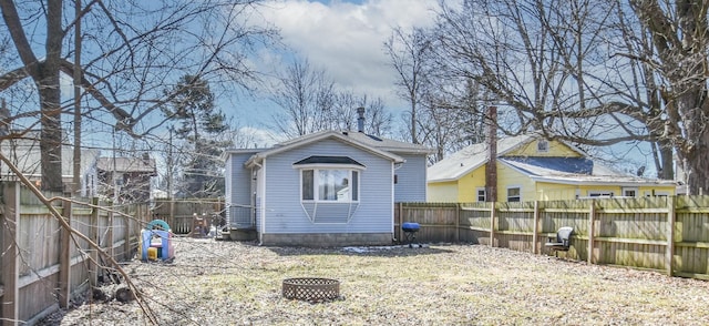 rear view of house featuring a fire pit and a fenced backyard