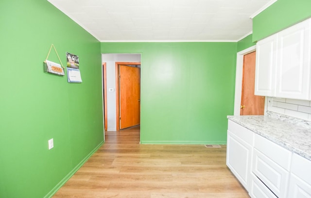 interior space with crown molding, baseboards, and light wood finished floors