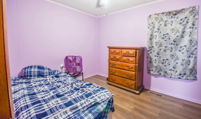 bedroom featuring baseboards, visible vents, light wood-type flooring, and ornamental molding