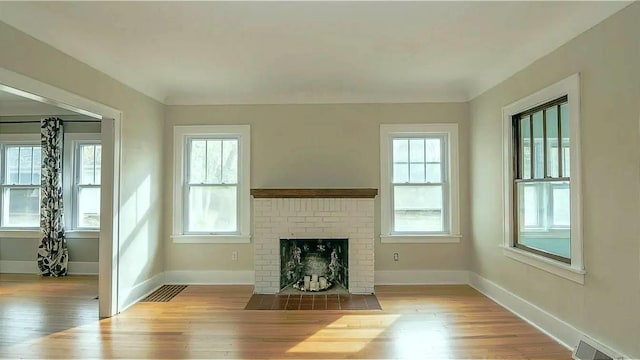 unfurnished living room featuring visible vents, baseboards, and wood finished floors