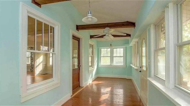 unfurnished sunroom featuring beam ceiling and ceiling fan