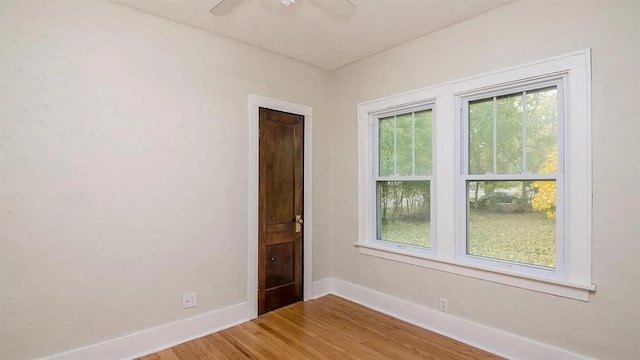 empty room with a ceiling fan, wood finished floors, and baseboards