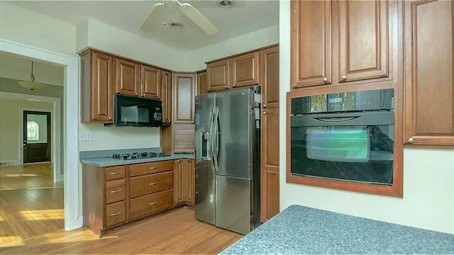 kitchen with black appliances, light wood-style flooring, a ceiling fan, brown cabinetry, and light countertops