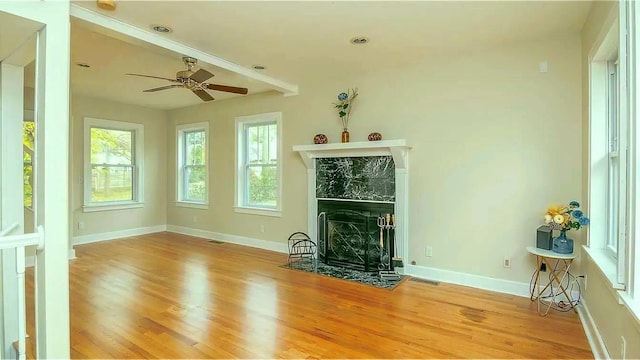 unfurnished living room with a high end fireplace, visible vents, baseboards, and wood finished floors