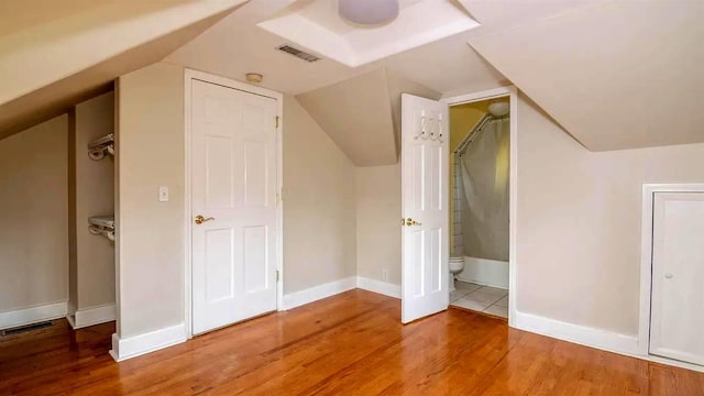 additional living space with visible vents, baseboards, wood finished floors, and vaulted ceiling