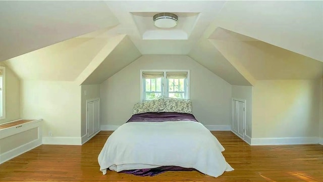 bedroom featuring baseboards, lofted ceiling, and wood finished floors