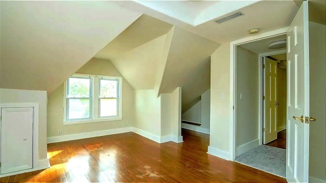 additional living space with visible vents, baseboards, lofted ceiling, and wood finished floors