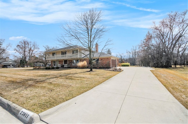 view of front of property with a balcony, a chimney, a front lawn, concrete driveway, and brick siding