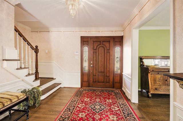 foyer with a decorative wall, ornamental molding, stairs, and dark wood-style flooring