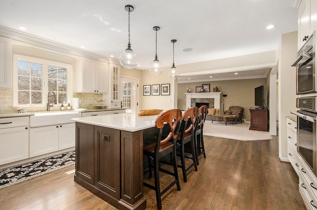 kitchen featuring a sink, oven, light countertops, white cabinets, and a kitchen breakfast bar