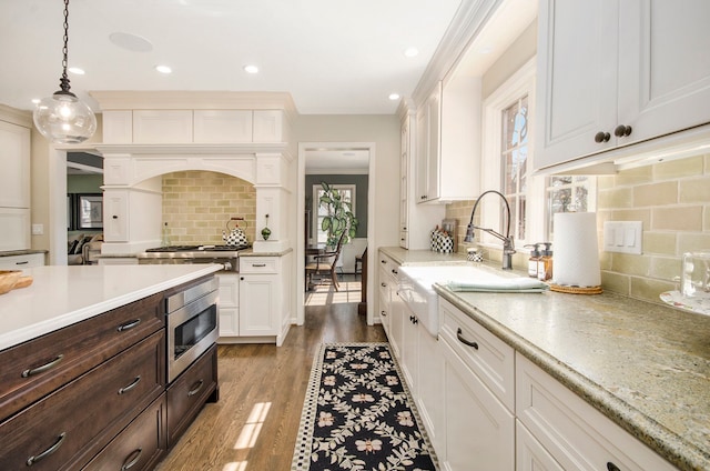 kitchen featuring a sink, wood finished floors, appliances with stainless steel finishes, and white cabinets