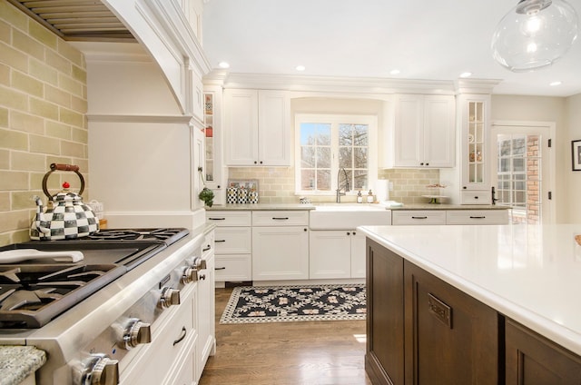 kitchen featuring a sink, dark wood finished floors, light countertops, glass insert cabinets, and stainless steel gas cooktop