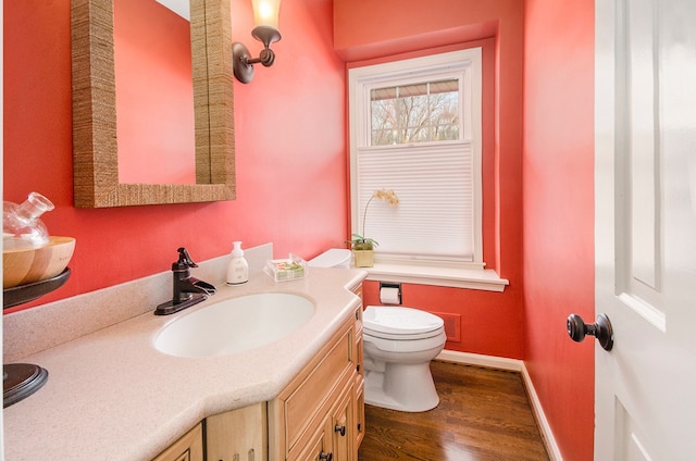 bathroom with baseboards, toilet, wood finished floors, and vanity