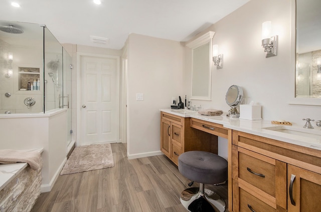 bathroom with double vanity, a sink, a stall shower, and wood finished floors