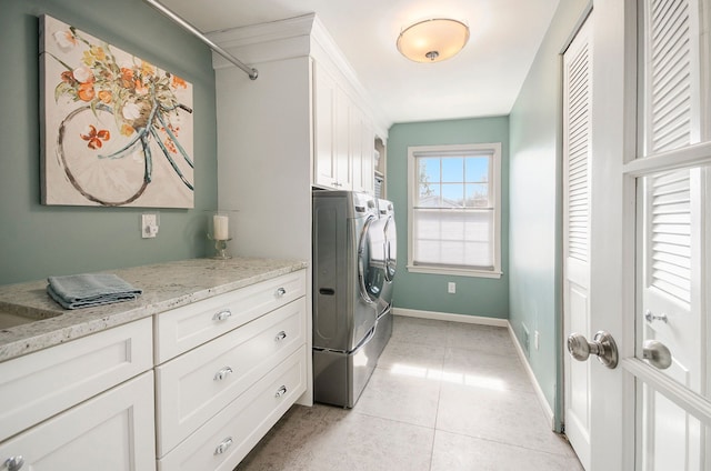 washroom with light tile patterned floors, baseboards, cabinet space, and separate washer and dryer