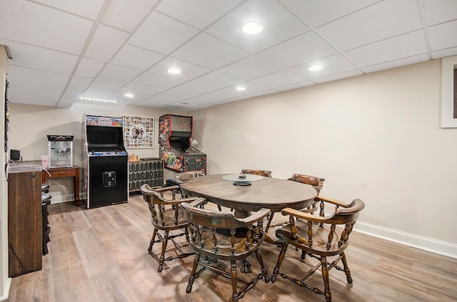 dining room featuring light wood finished floors, a drop ceiling, recessed lighting, and baseboards