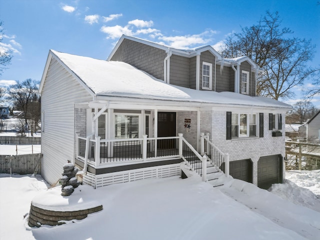 view of front facade featuring a porch, an attached garage, fence, and brick siding