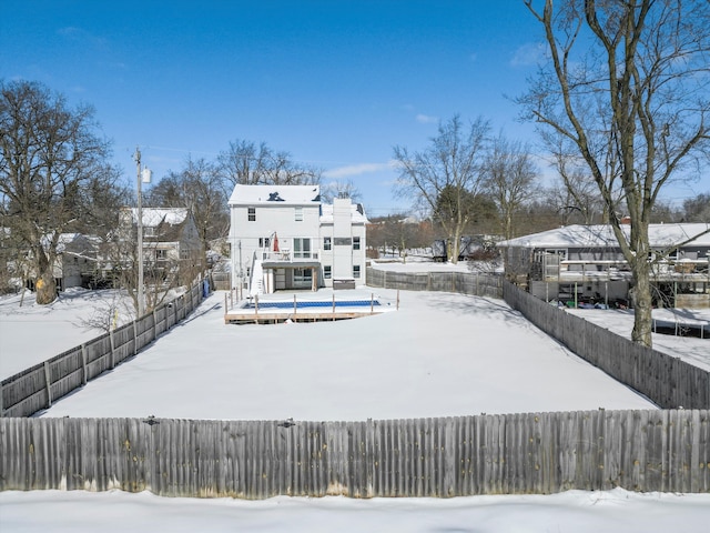 snow covered property with a fenced backyard and a wooden deck